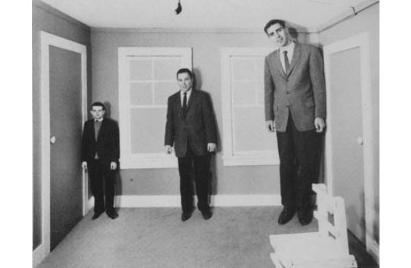 Рис. 2.8. Комната Эймса. Изобретение Эдельберта Эймса-младшего (Adelbert Ames, Jr.) от 1946 года, основанное на идее Гельмгольца. Все три человека на самом деле одинакового роста, но пропорции комнаты искажены.\nИсточники: Wittreich, W. J. (1959). Visual perception and personality, Scientific American, 200(4), 56–60 (58). Фотография предоставлена Уильямом Вандивертом.\n