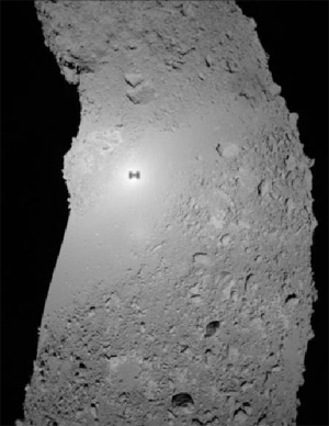 Тень станции «Хаябуса» на поверхности астероида Итокава. Снимок сделан 19 ноября в 22:58 по московскому времени с высоты около 350 м. Хорошо видно, что грунт астероида намного сильнее рассеивает свет в направлении прямо противоположном его приходу (то есть обратно к Солнцу), чем под углом. Из-за этого ближе к краям снимка поверхность темнеет (фото с сайта www.isas.ac.jp)