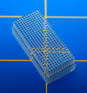 Прозрачный кристалл LYSO компании Saint-Gobain лежит на зеркальной подложке и размечен для разрезания на отдельные детекторы миллиметрового размера. Фото: Saint-Gobain («Химия и жизнь» №11, 2021)