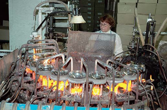 На одном автомате одновременно идёт работа с несколькими десятками будущих ламп. На фото: приваривание ножки к горловине колбы. Фото: «Наука и жизнь»