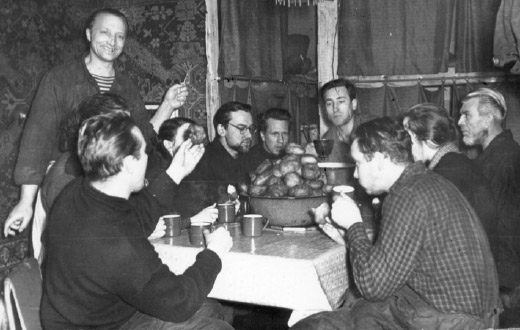 Повар Александр Карасев (стоит) приготовил праздничный ужин — пончики. В. Суходровский (спиной), А. Карасев, Н. Разумейко, А. Кренке, В. Маркин, И. Пархоменко, В. Толмачев, Л. Базанов, О. Виноградов. Изображение: «Химия и жизнь»