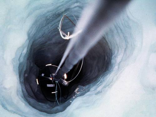 Подледная рыбалка. Ученые опускают в отверстие глубиной около 2 км в ледяном панцире Антарктиды трос с прикрепленными к нему чувствительными фотодетекторами, которые образуют нейтринный телескоп AMANDA (Antarctic Muon and Neutrino Detector Array). Земной шар служит защитным фильтром для этого телескопа, регистрирующего нейтрино из глубин космоса. Изображение: «Популярная механика»