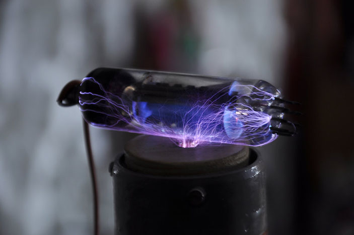 Высокочастотные разряды (12 кГц, 30 кВ) огибают диэлектрическую поверхность стеклянного баллона старой радиолампы («Популярная механика» №4, 2019)