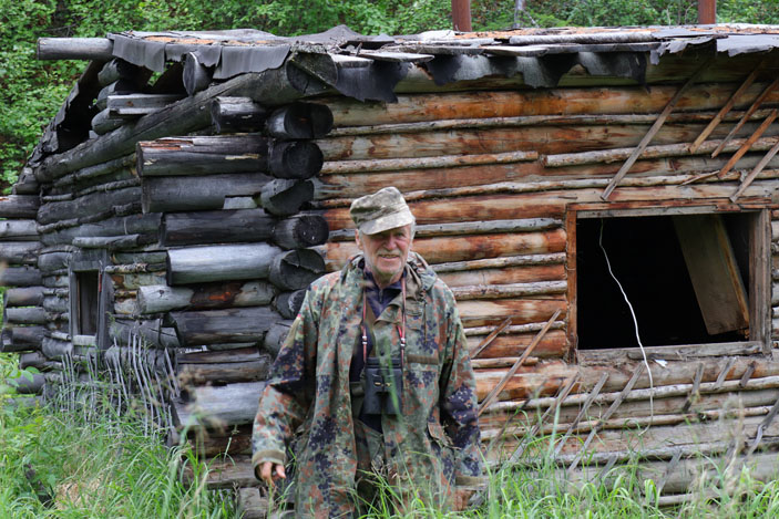 А. В. Андреев на фоне остатков избы знаменитого стационара на р. Омолон («Троицкий вариант» №1, 2021)
