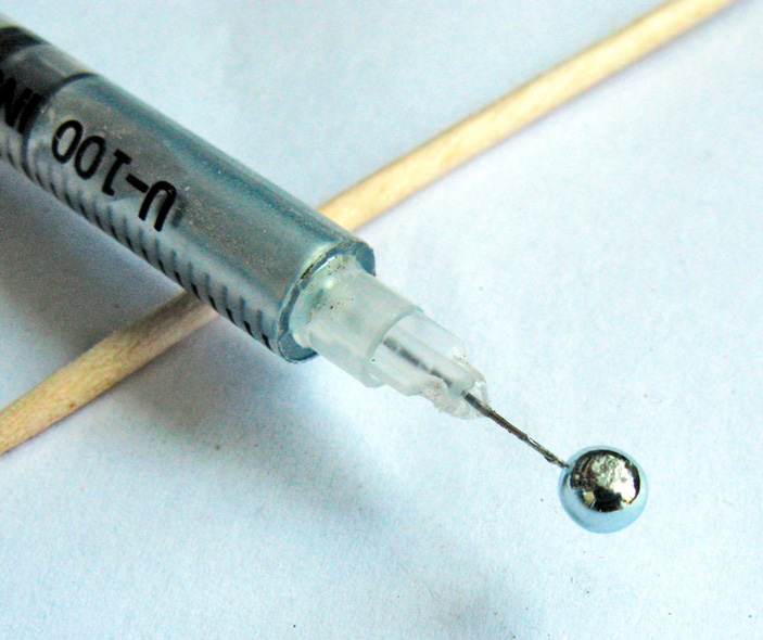 Лето. Жара. Жидкий галлий набрали в шприц, и он под действием тепла стал оттуда выдавливаться. Однако оксидная пленка на поверхности капли не дает ей упасть. Фото: М.Ю. Корнилов («Химия и жизнь» №9, 2021)