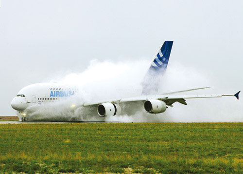 А-380 совершает посадку на полосу, покрытую водой. Испытания показали, что самолет способен садиться при боковом ветре с порывами до 74 км/ч (20 м/с). Хотя согласно требованиям FAA и EASA устройства реверсивного торможения не являются обязательными, конструкторы компании <i>Airbus</i> решили оснастить ими два двигателя, находящиеся ближе к фюзеляжу. Это дало возможность получить дополнительную тормозную систему, снизив при этом эксплуатационные расходы и уменьшив время подготовки к следующему полету. Изображение: «Популярная механика»